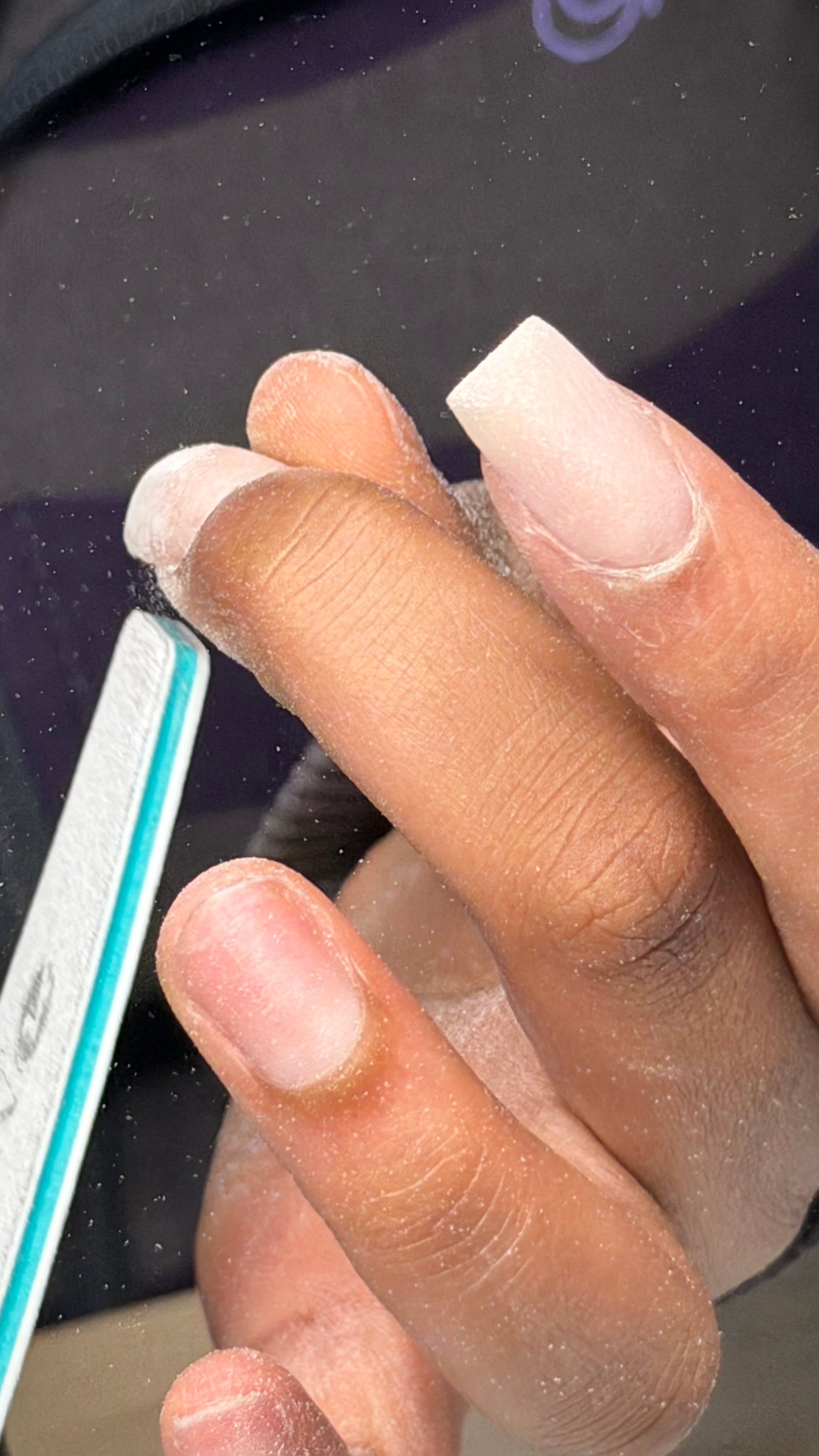 Student filing an acrylic nail on an in person acrylic course