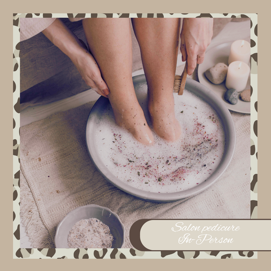 Person getting a foot soak with a bowl of water and scrub, surrounded by candles and stones.